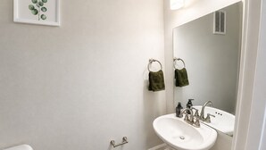 A bathroom with a toilet, sink, and mirror.