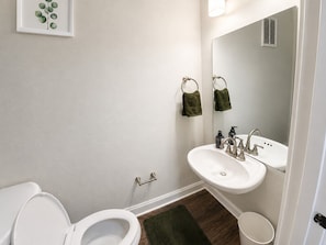 A bathroom with a toilet, sink, and mirror.