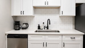 A kitchen with white cabinets, a stainless steel sink, and a dishwasher.