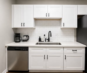 A kitchen with white cabinets, a stainless steel sink, and a dishwasher.