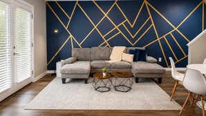 Ein Wohnzimmer mit einer Couch, zwei Couchtischen und einem gemusterten Teppich.