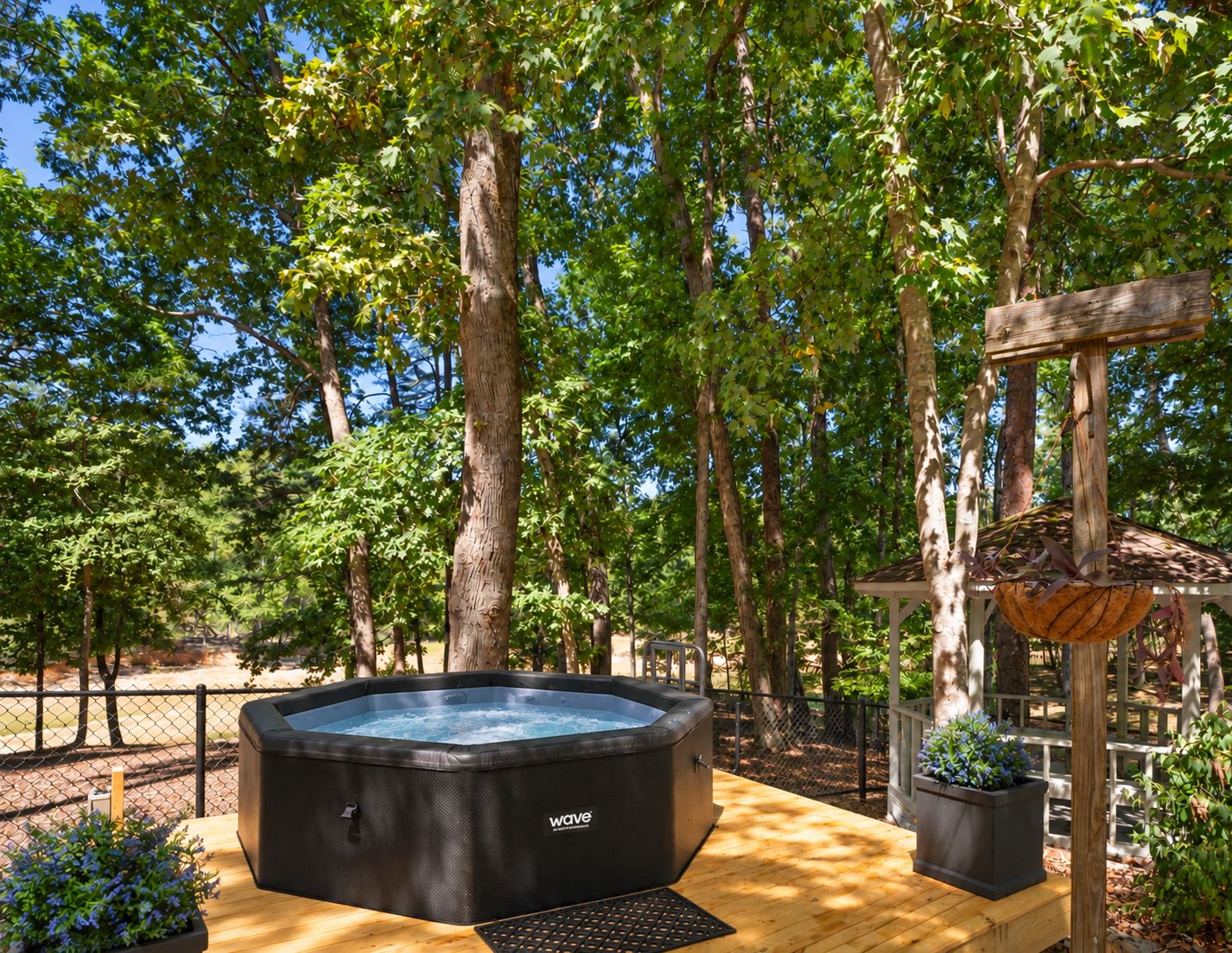 Un jacuzzi en una terraza de madera rodeado de árboles.