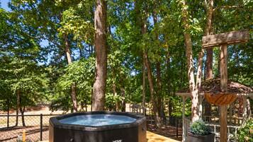 Un jacuzzi en una terraza de madera rodeado de árboles.