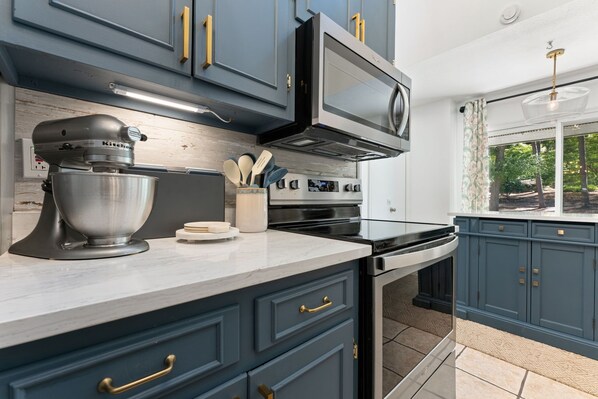 A kitchen with dark blue cabinets, a stainless steel range, and a stand mixer.