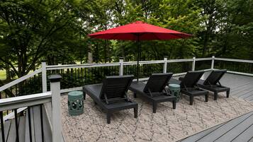 Eine Terrasse mit Gartenmöbeln und einem roten Sonnenschirm.