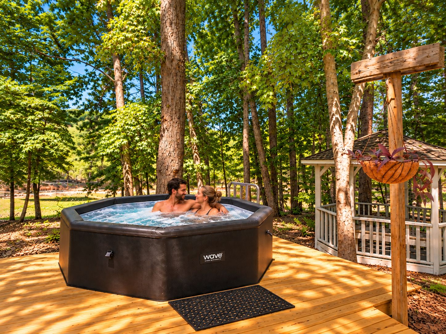 A hot tub with a wooden deck and a gazebo in a wooded area.