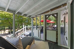 A covered outdoor seating area with a bench, a table, and a red umbrella.