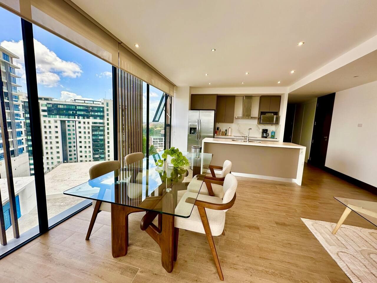 Un interior moderno con comedor, cocina y ventanas amplias con vistas a la ciudad.