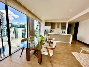 A modern interior with a dining area, kitchen, and large windows offering a city view. - New Luxury Condo 2BR/2BA | Zone 15 | Near Cayalá! (Guatemala City)