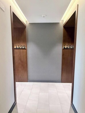 A hallway with two doors labeled 1105 and 1106, leading to rooms. The floor is tiled, and the walls are painted in a neutral color. - New Luxury Condo 2BR/2BA | Zone 15 | Near Cayalá! (Guatemala City)