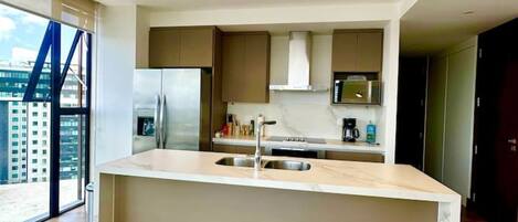 A modern kitchen with a central island, stainless steel appliances, and a view of the city.