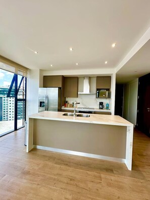 A modern kitchen with a central island, stainless steel appliances, and a view of the city. - New Luxury Condo 2BR/2BA | Zone 15 | Near Cayalá! (Guatemala City)