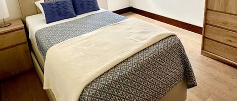 Un dormitorio con cama, mesita de noche, ventana y armario.