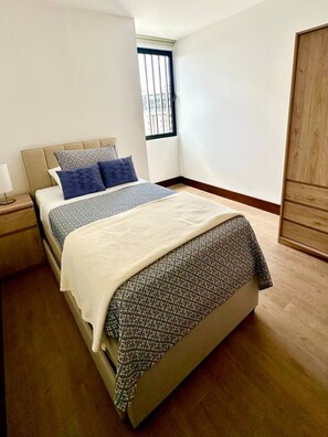 Ein Schlafzimmer mit einem Bett, einem Nachttisch, einem Fenster und einem Kleiderschrank.
