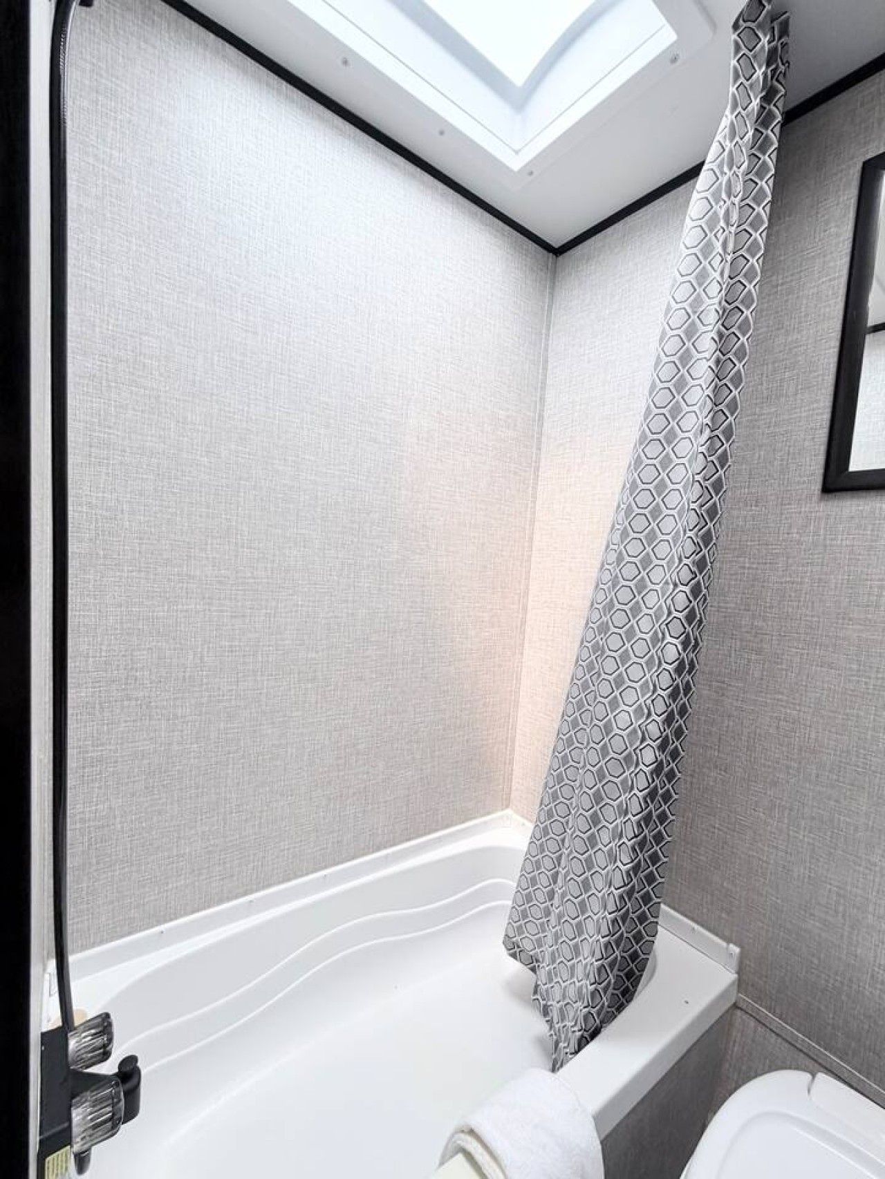 Ein Badezimmer mit Dachfenster, einer Badewanne und einer Toilette.