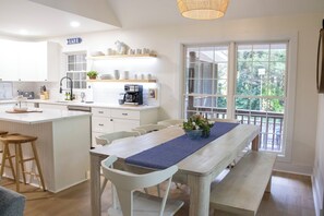 Una cucina moderna con mobili bianchi, una macchina da caffè e un'area pranzo con una panca e sedie.