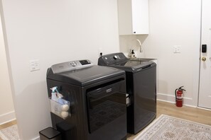 A laundry area with two washing machines, a small sink, and a fire extinguisher.