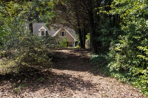 Una casa circondata da un bosco fitto, con un sentiero sterrato che conduce all'ingresso.