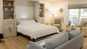 Un dormitori amb llit, sofà, cadira, ventilador de sostre i finestra.