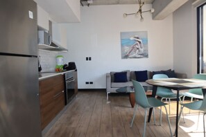 A modern kitchen with wooden cabinets, a built-in oven, and a dining area with a round table and chairs. - EON Zone 10: Luxury, views, and comfort—all in one place. (Ciudad de Guatemala)