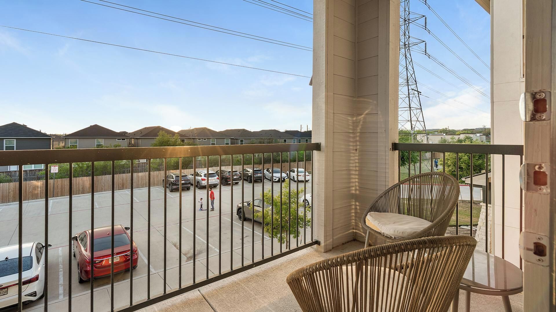 A balcony with a view of a parking lot and houses.