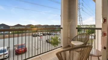 A balcony with a view of a parking lot and houses.