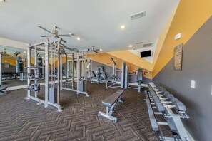 Un gimnasio con varios equipos de ejercicio, un espejo grande y una alfombra estampada.