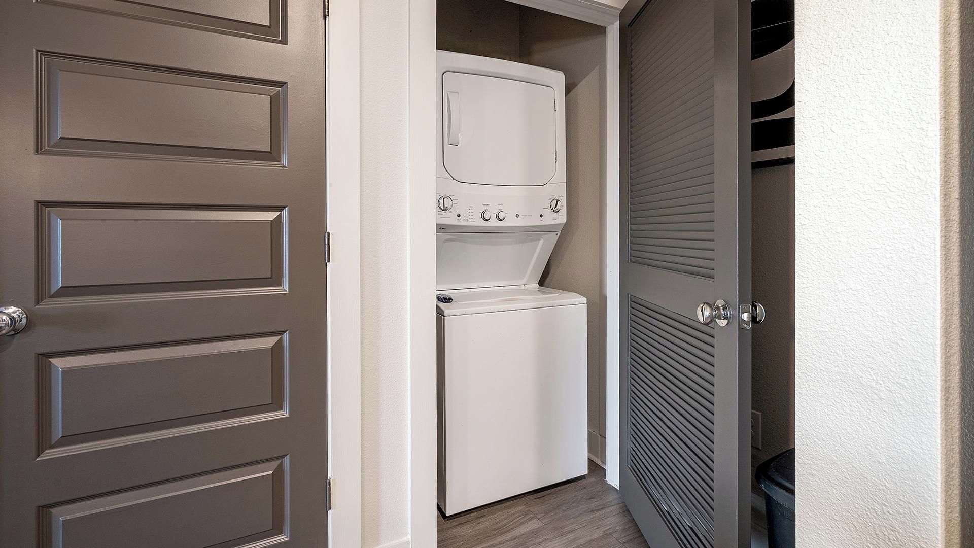 A laundry room with a washer and dryer, a door with a handle, and a vented wall.
