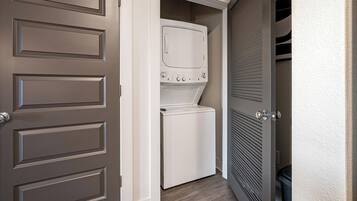 A laundry room with a washer and dryer, a door with a handle, and a vented wall.