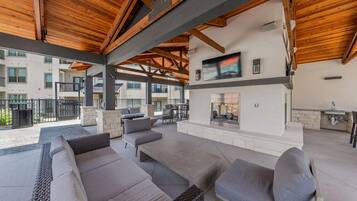 An outdoor patio with seating, a fireplace, and a TV mounted on the wall.