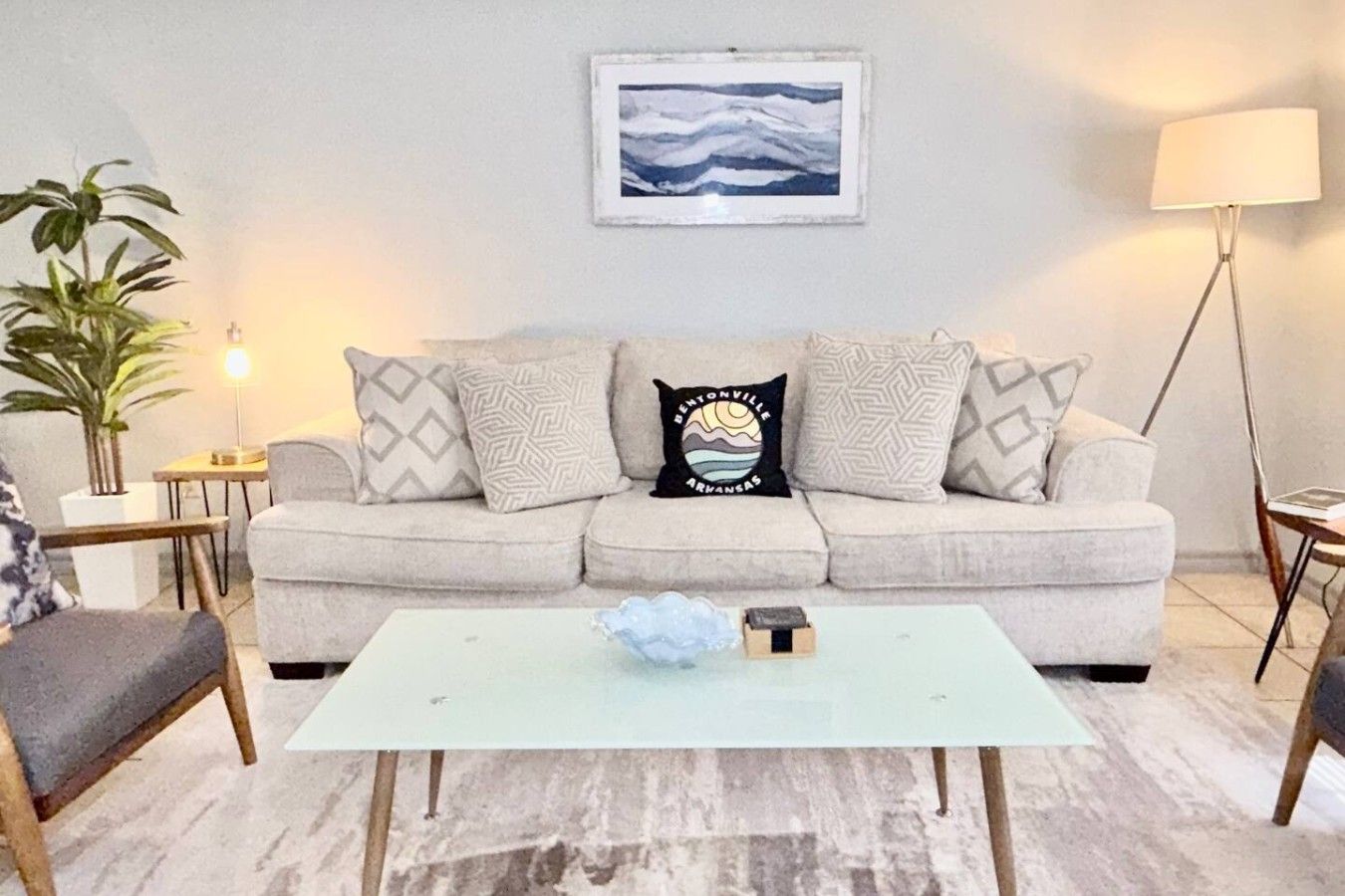 A living room with a sofa, a coffee table, a lamp, and a framed picture on the wall.