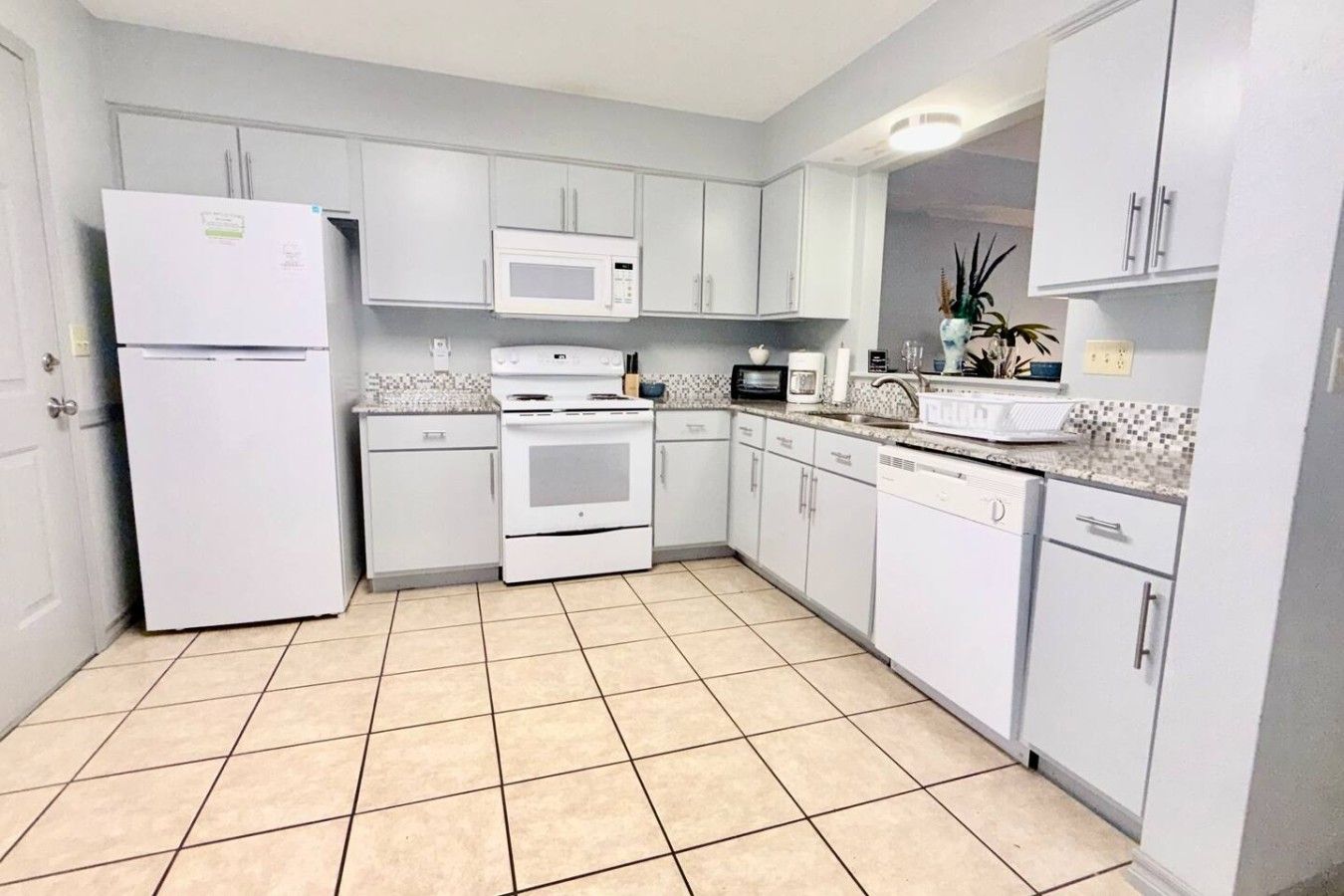 A kitchen with white cabinets, a refrigerator, a microwave, an oven, and a dishwasher.