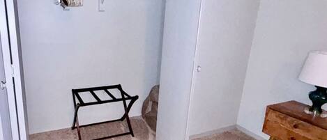 A closet with hanging space, a small wooden table, and a lamp.