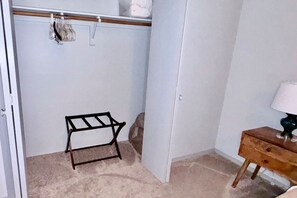 A closet with hanging space, a small wooden table, and a lamp. - Top Stay in a Perfect Location – Crystal Bridges (Bentonville)