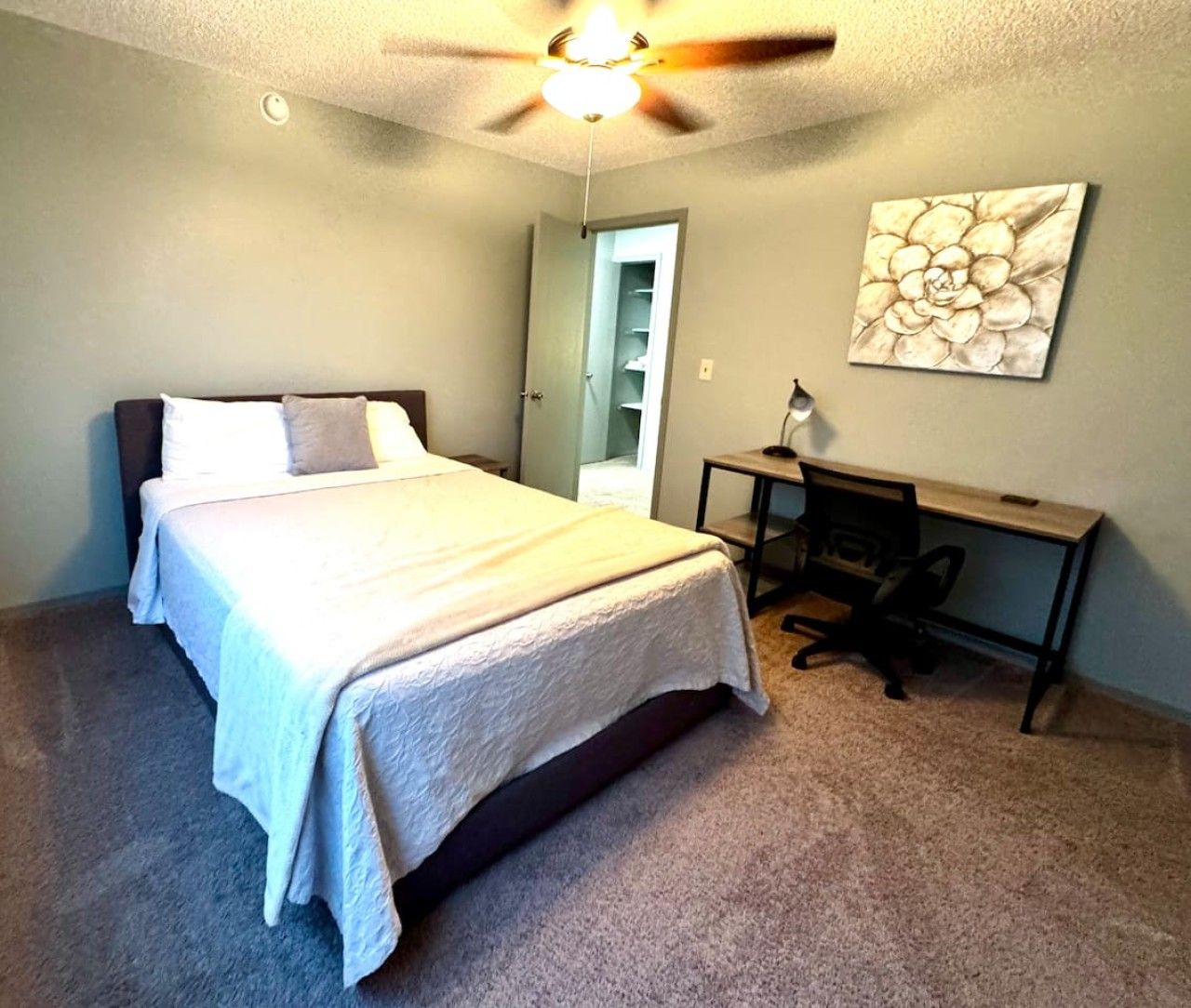 Une chambre à coucher avec un lit, un bureau et un ventilateur de plafond.