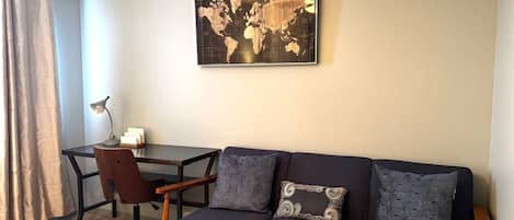 Une pièce avec un canapé sombre, une chaise en bois, une petite table et une carte du monde accrochée au mur.