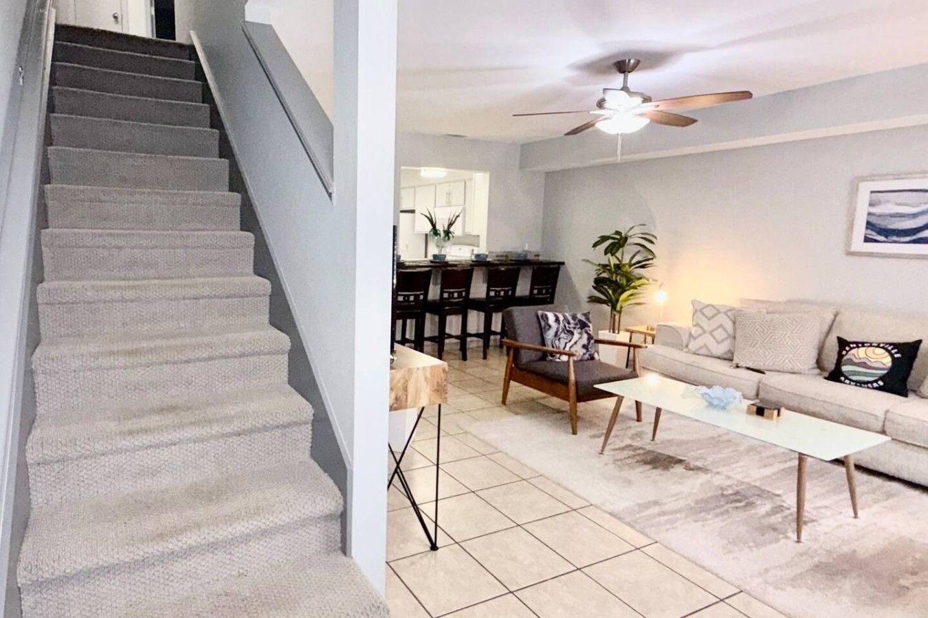 Un escalier menant à un espace de vie comprenant un canapé, une table basse et un ventilateur de plafond.