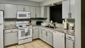 A compact kitchen with white cabinets, a microwave, stove, and a coffee maker. - Top Stay in a Perfect Location – Crystal Bridges (Bentonville)