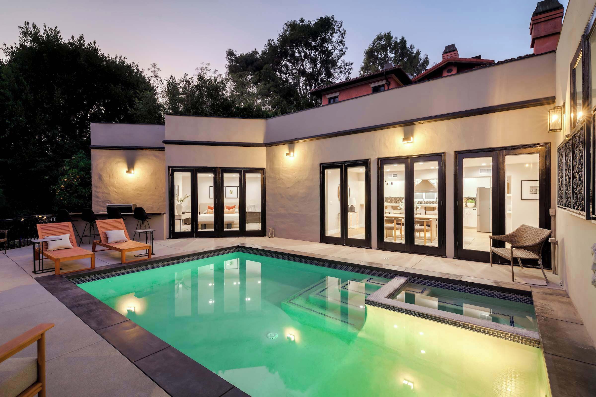 Une maison moderne dotée d’une piscine, d’un espace extérieur aménagé et d’un intérieur bien éclairé.