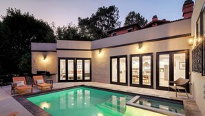 Uma casa moderna com piscina, área de estar externa e interior bem iluminado.