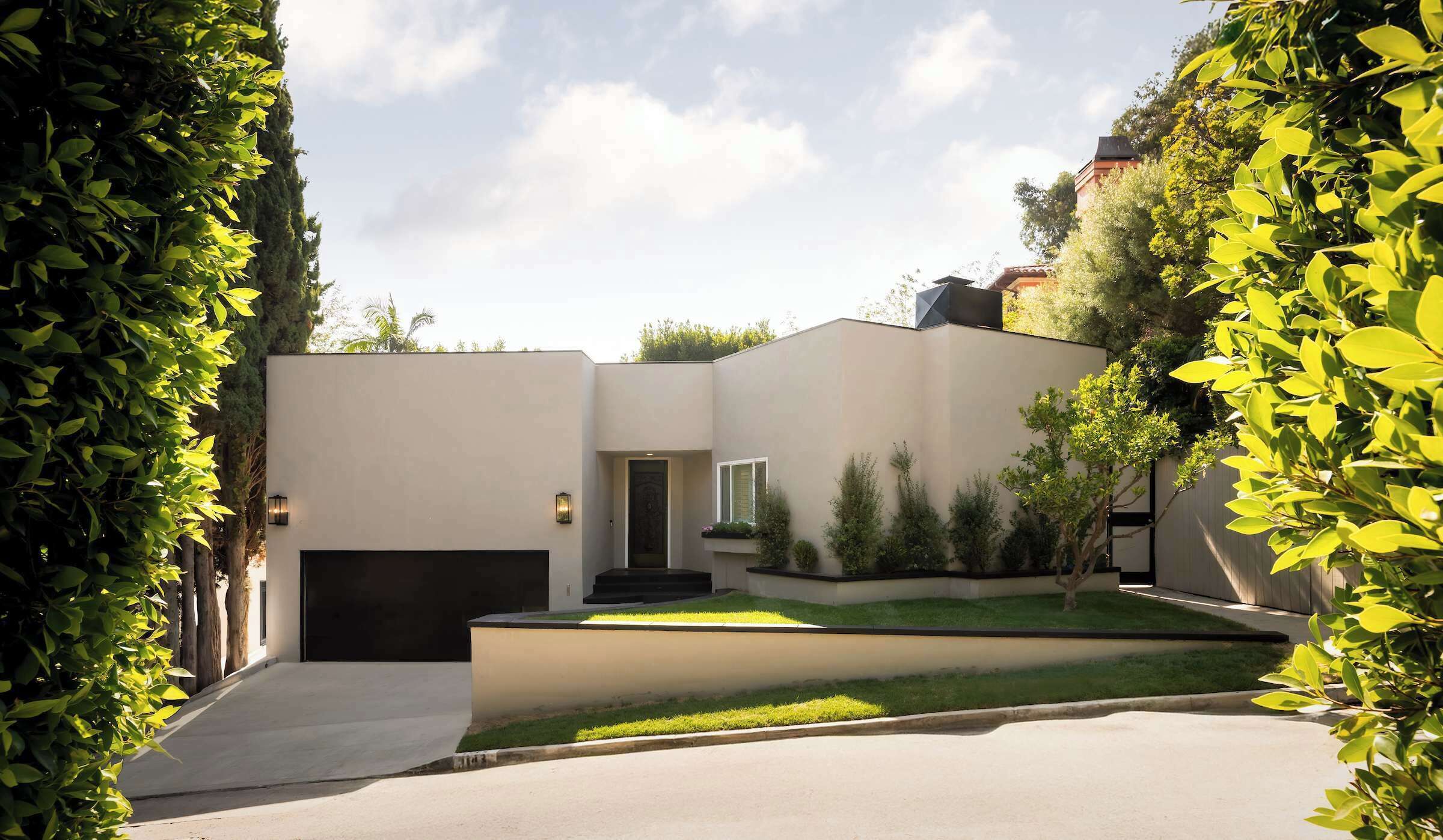 A modern house with a garage, a small front yard, and a driveway.