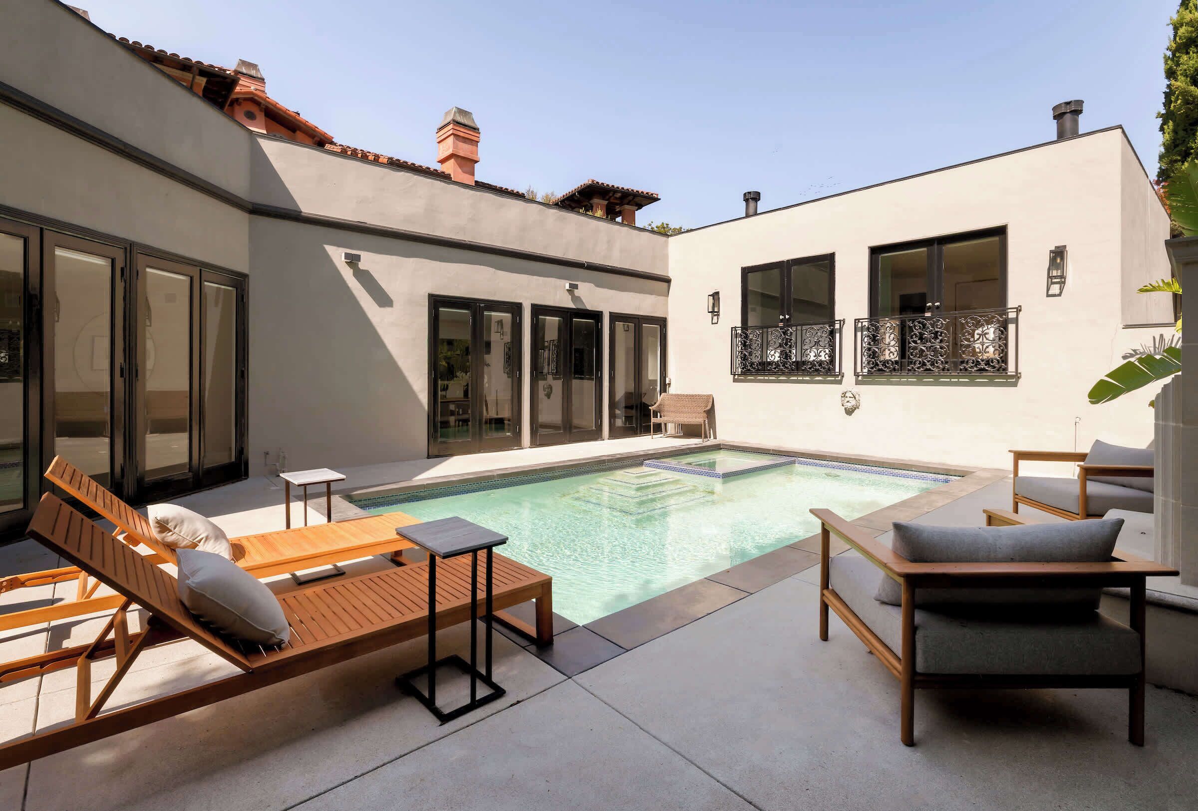 A modern outdoor pool area with lounge chairs and a small table.