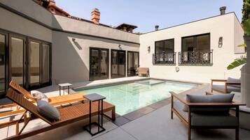 A modern outdoor pool area with lounge chairs and a small table.