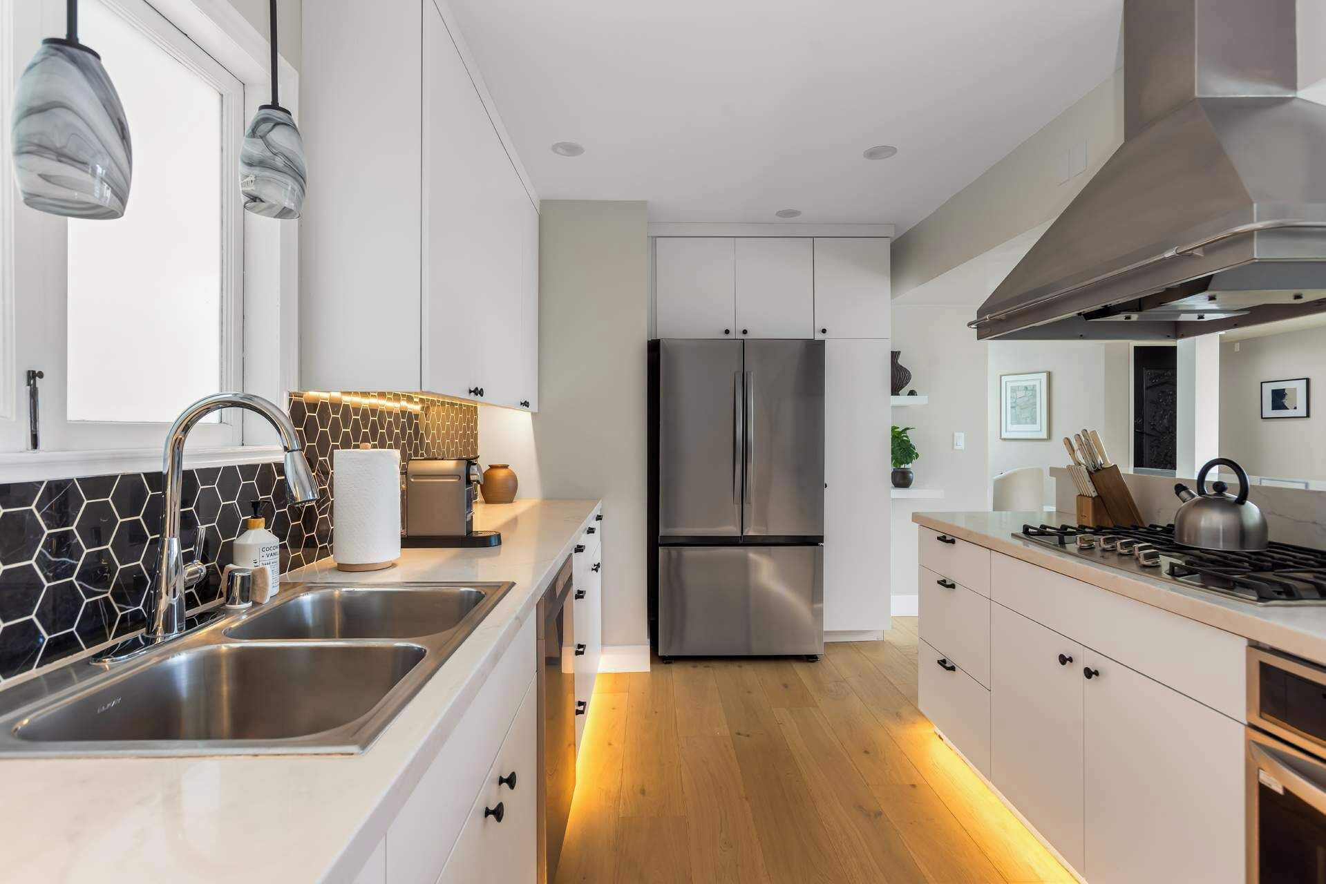 A modern kitchen with a stainless steel refrigerator, a gas stove, and a double sink.