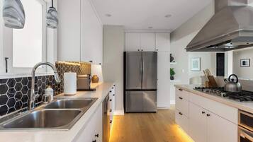 A modern kitchen with a stainless steel refrigerator, a gas stove, and a double sink.