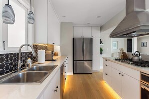 Eine moderne Küche mit einem Edelstahl-Kühlschrank, einem Gasherd und einer Spüle.