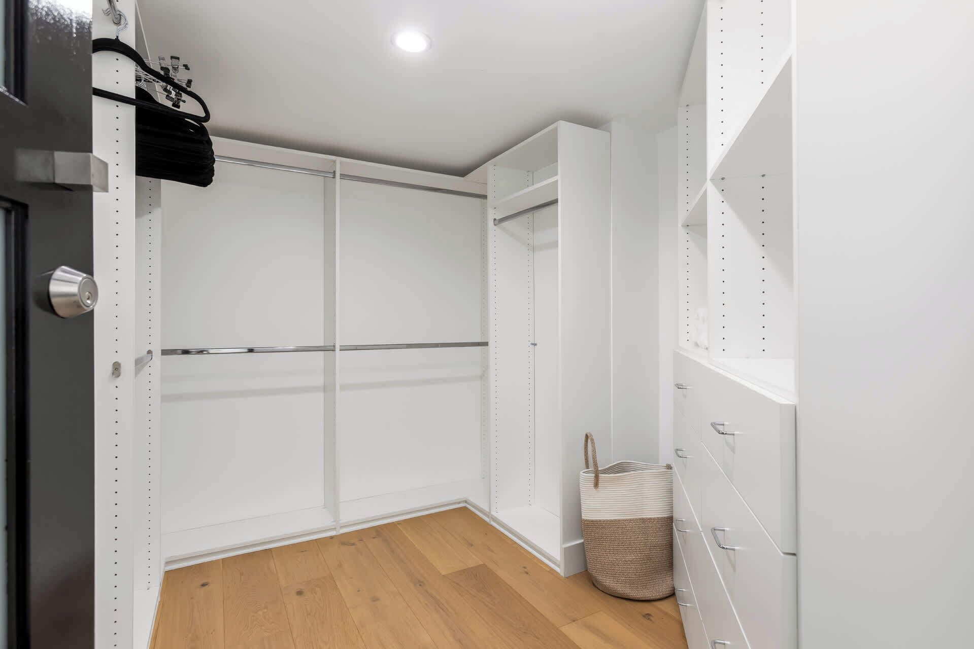 A room with a wooden floor, white walls, and a door with a metal handle.