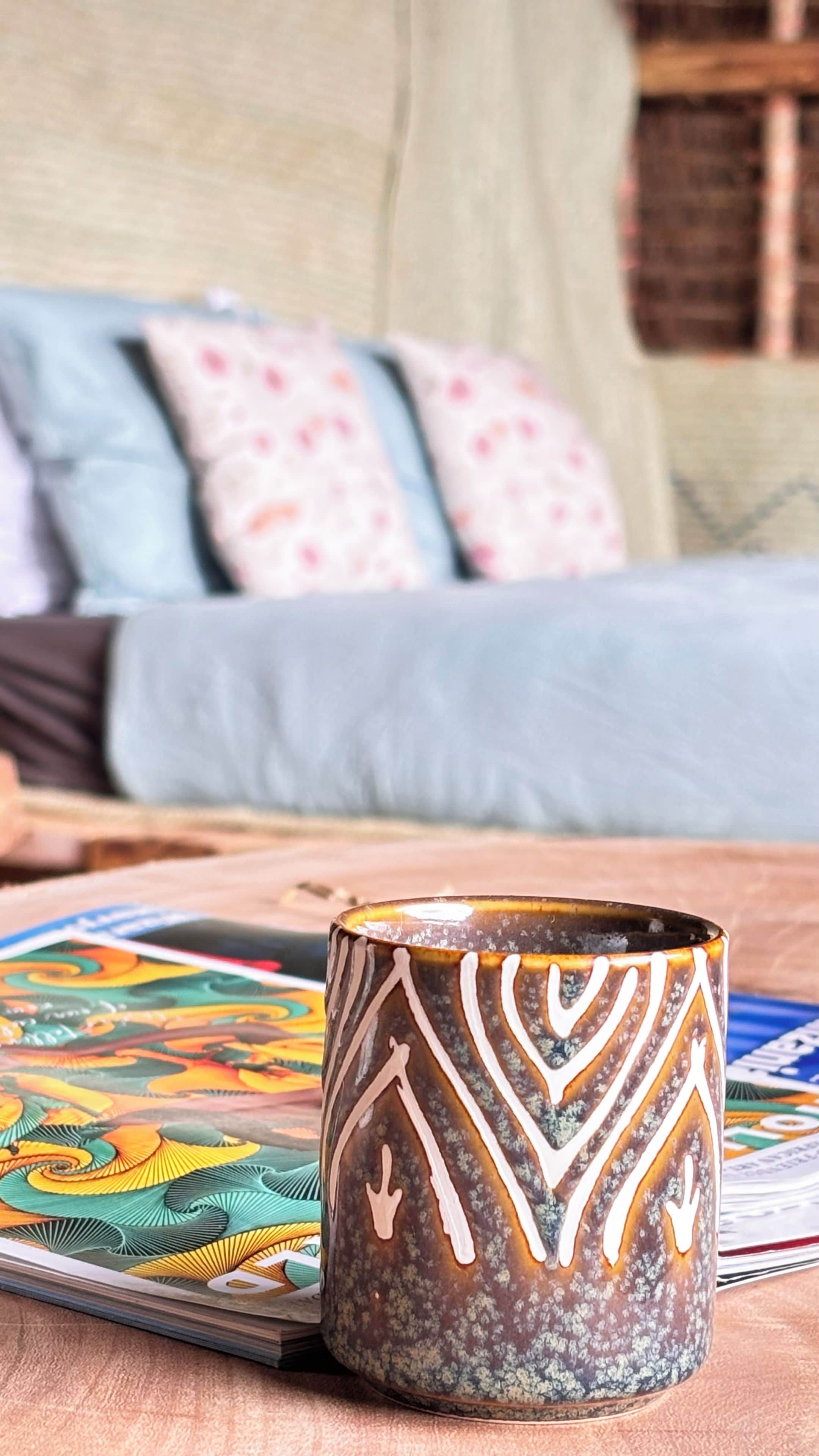 A mug with a geometric pattern on a table, with a colorful card game nearby.