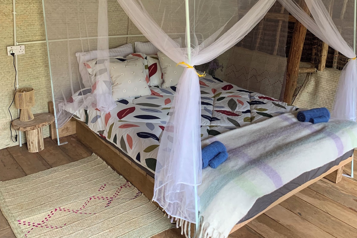 Un lit à baldaquin, avec des oreillers, une couverture et une petite table sur laquelle se trouve une lampe.