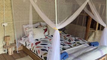 Een bed met baldakijn, een geweven vloerkleed en een houten vloer.